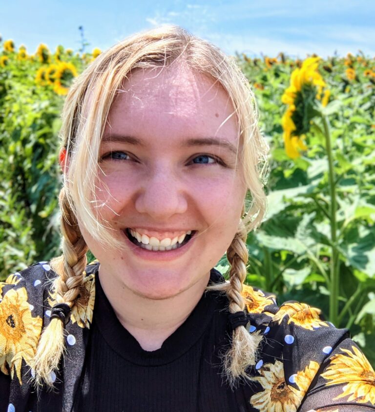 The author (a blonde woman) standing in front of sunflowers